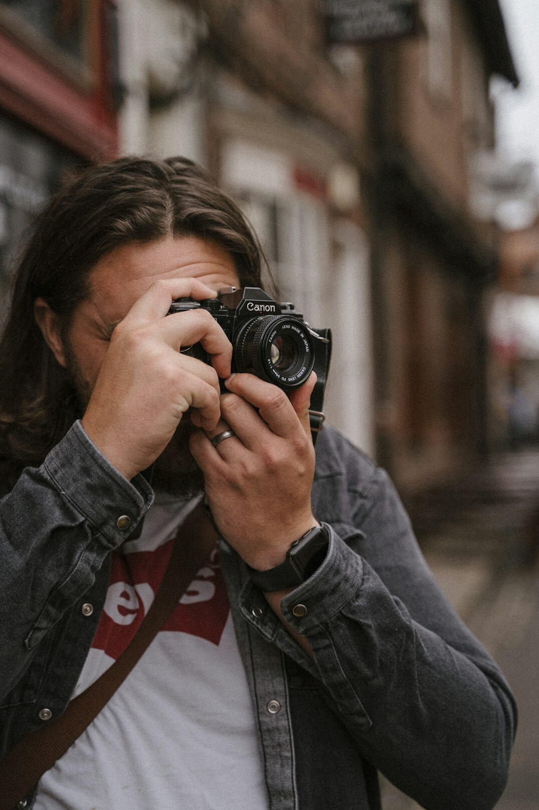 Studio portrait of a Danish male photojournalist with a camera strap over his shoulder