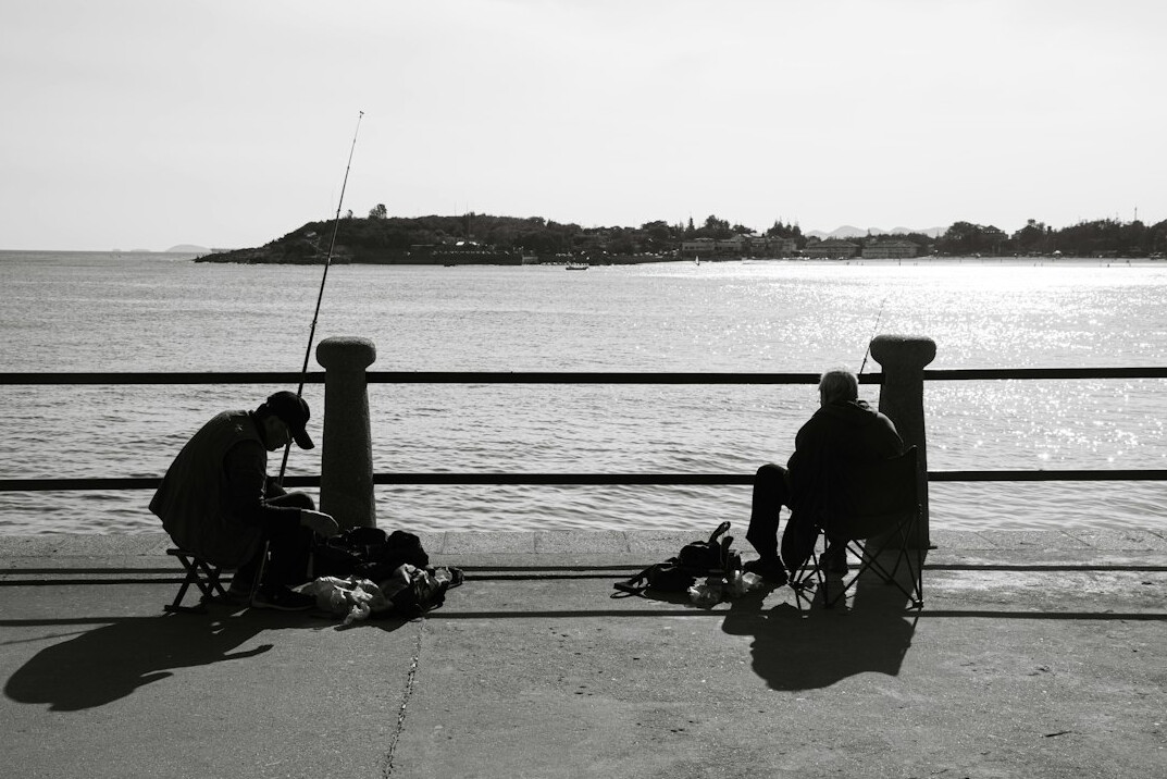 Group of elderly Danish fishermen mending nets and talking on a harbor pier